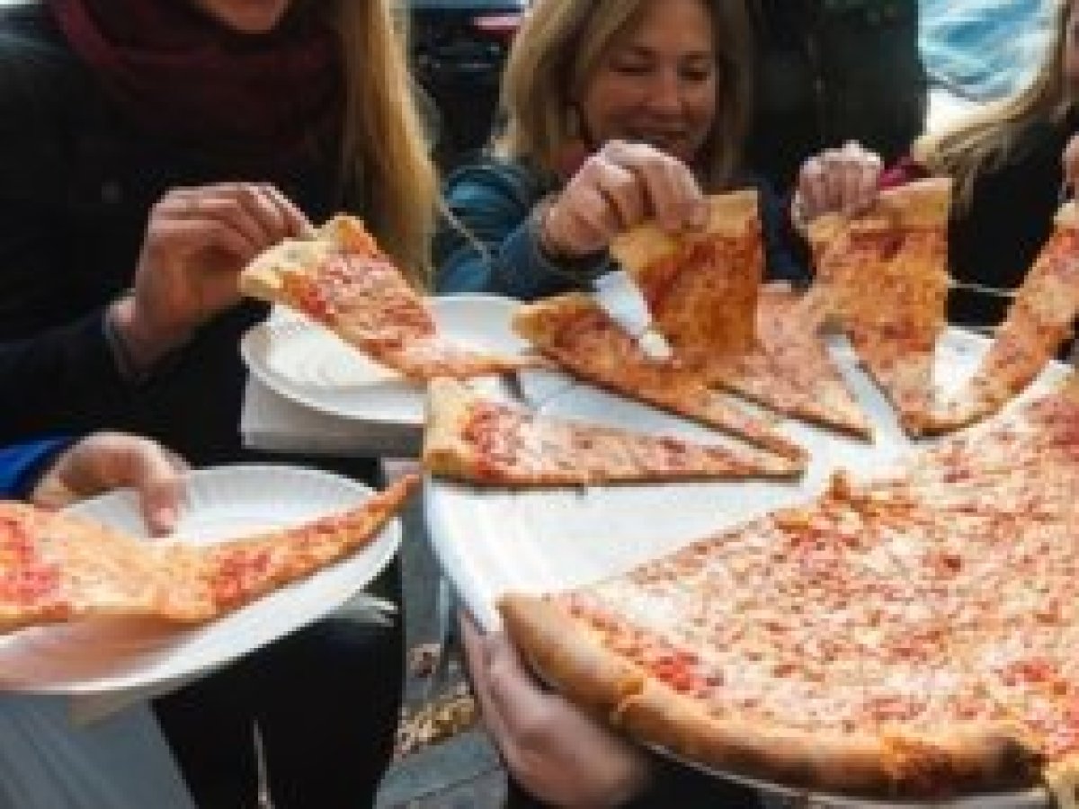 a group of people sitting at a table eating pizza